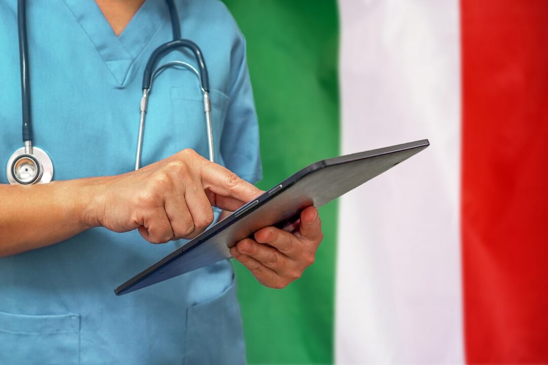 Surgeon Or Doctor Using A Digital Tablet On The Background Of The Italy Flag.