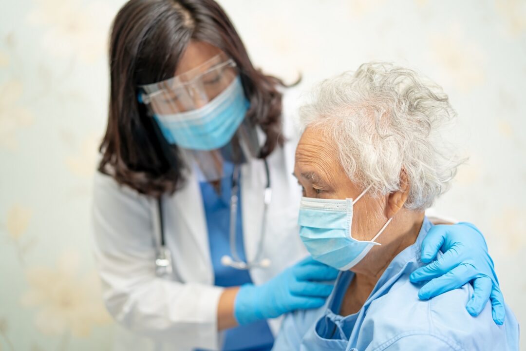 Asian Doctor Wearing Face Shield And PPE Suit To Check Patient P