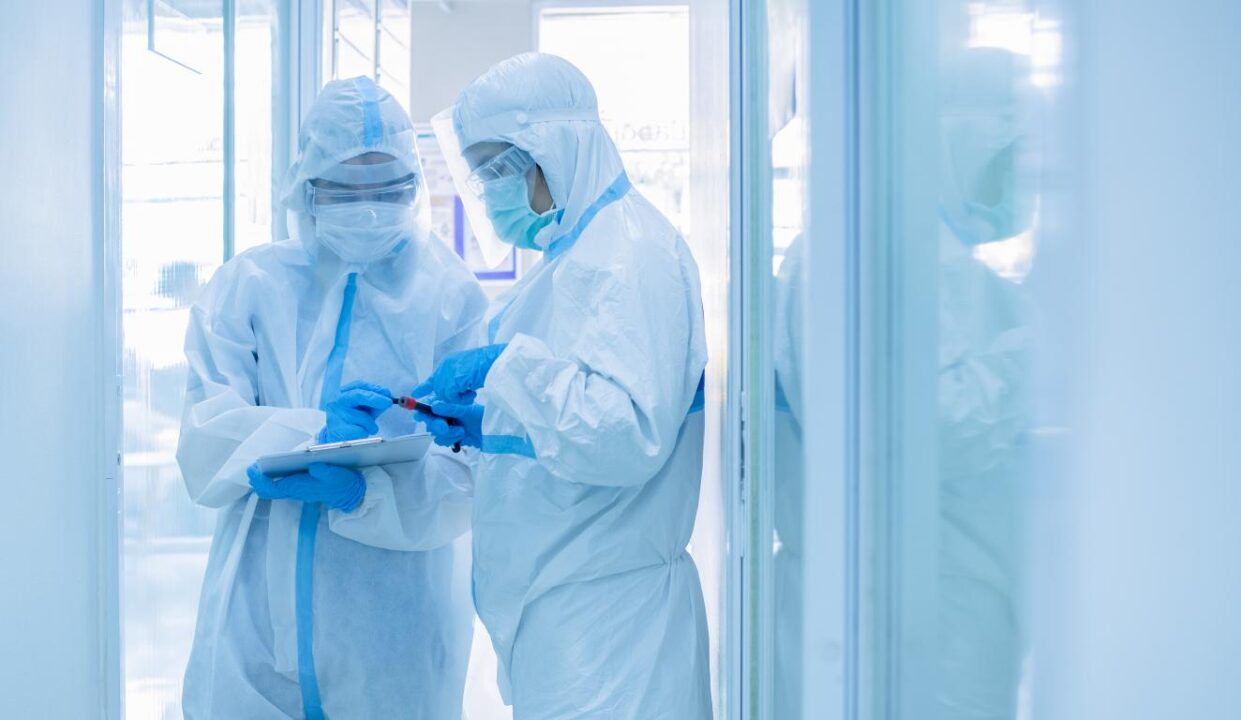 Asian Woman Doctor In Personal Protective Suit With Mask Writing On Quarantine Patient Chart Holding Test Tube With Blood 4