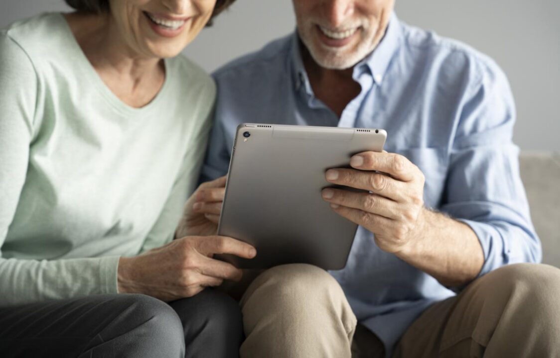 Close Up Smiley Seniors With Tablet