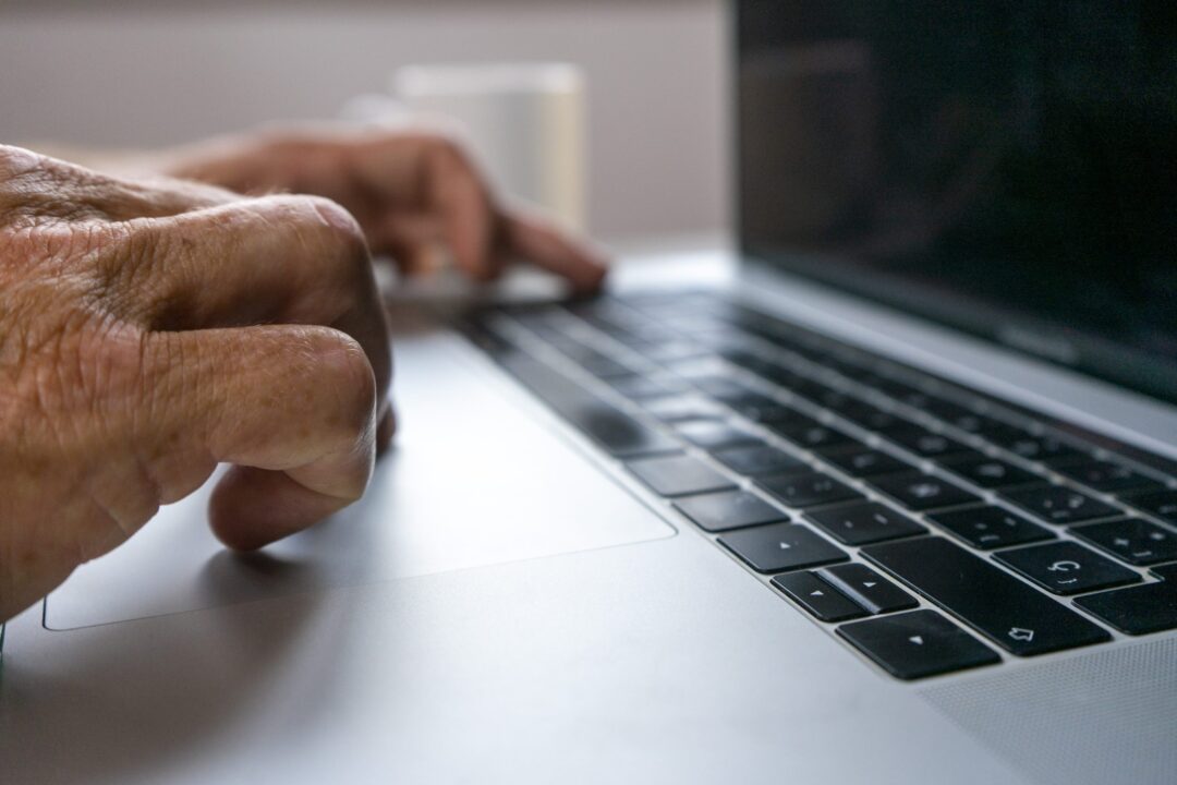 closeup-of-hands-of-an-older-man-working-on-a-laptop-scaled