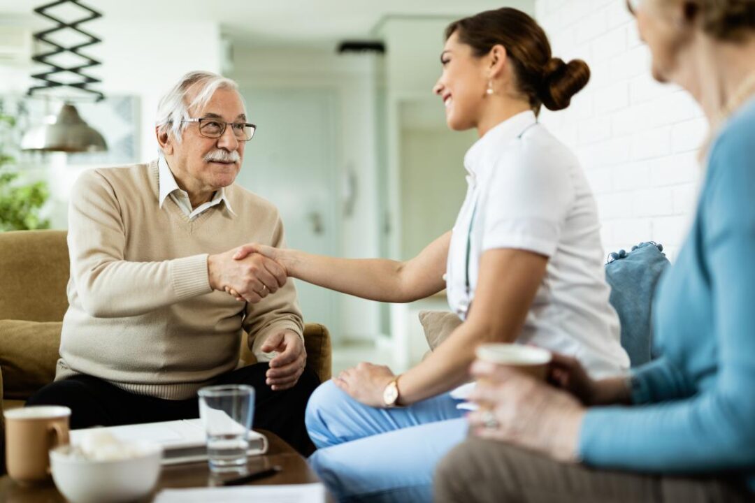 Happy Mature Man Shaking Hands With Female Nurse Who Is Visiting Him Home 1