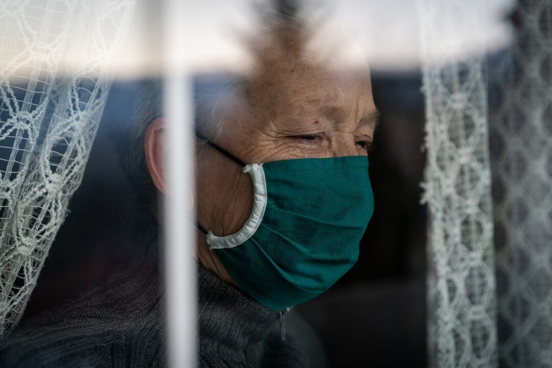 Senior Woman In Quarantine Crying On Window
