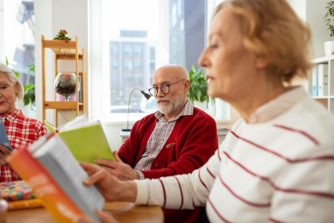 Love Reading Pleasant Aged Man Holding Green Book While Reading It Together With Friends