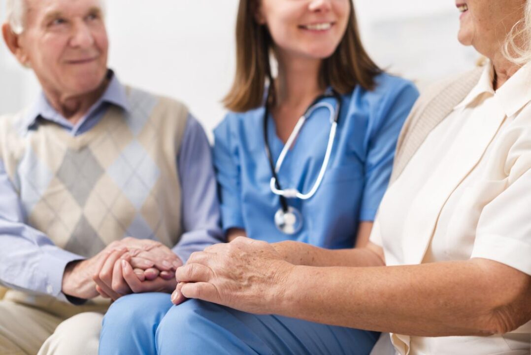 Old Man And Woman Sitting On Yellow Sofa With Nurse 1