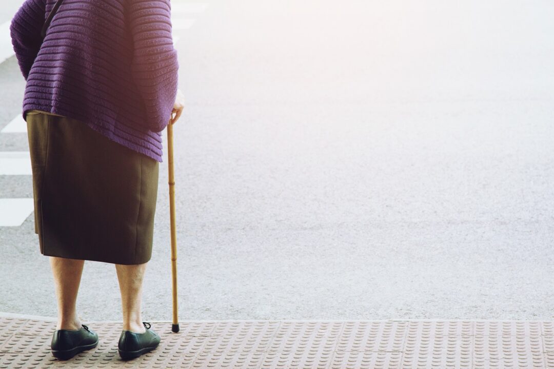 Elderly Old Woman With Walking Stick Stand Waiting On Footpath S