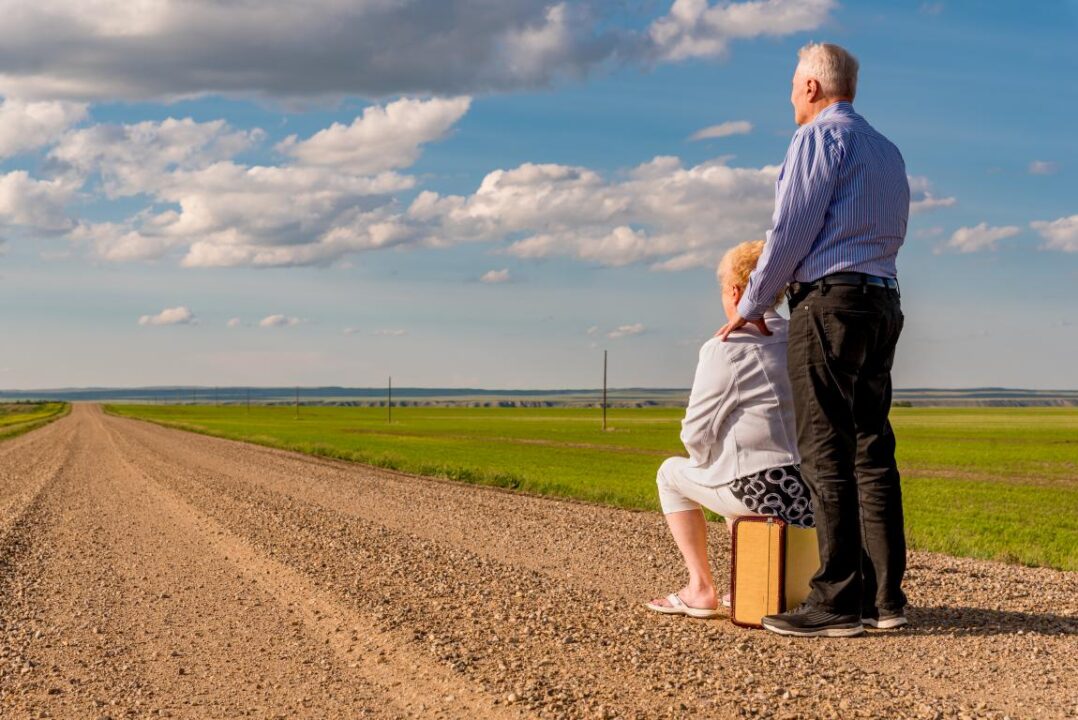 Senior Couple Sitting Vintage Suitcase Gravel Road Prairies Canada 1
