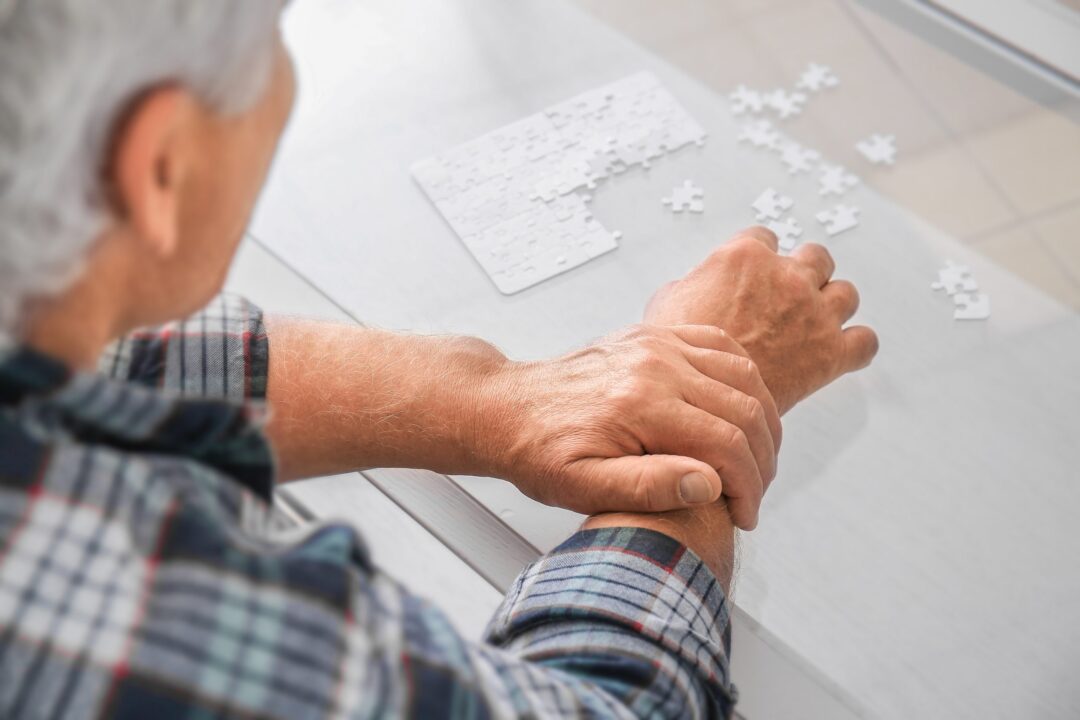 senior-man-with-parkinson-syndrome-doing-puzzle-home-scaled