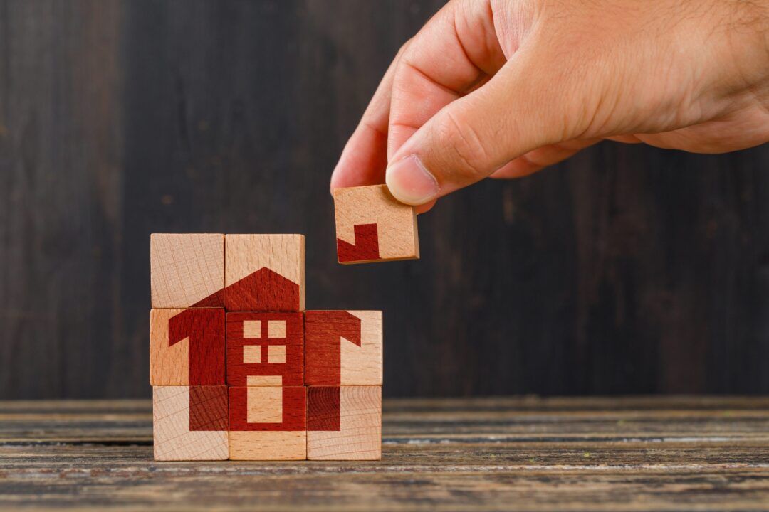 stay-at-home-concept-on-wooden-table-side-view-hand-holding-wooden-cube-scaled