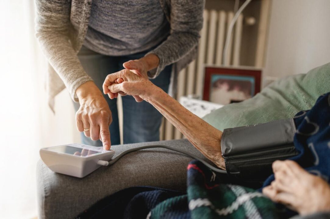 Unrecognizable Woman Measuring The Tension With Tensiometer To An Old Person Home Care And Assistance Elderly Concept